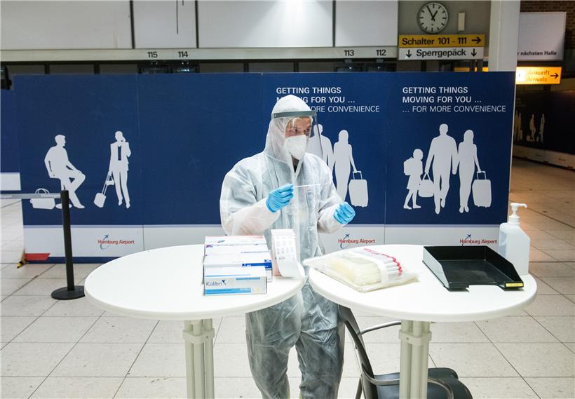 Ein Mitarbeiter des Deutschen Roten Kreuzes (DRK) steht am Hamburger Flughafen während eines Pressetermins mit einem Test-Wattestäbchen in einem Corona-Testzentrum. In Saarbrücken hat nun auch ein Testzentrum für Reiserückkehrer eröffnet.
