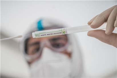 Ein Mitglied des medizinischen Personals steckt ein Wattestäbchen nach einem PCR-Abstrich zum Test auf Covid-19 in ein Röhrchen
