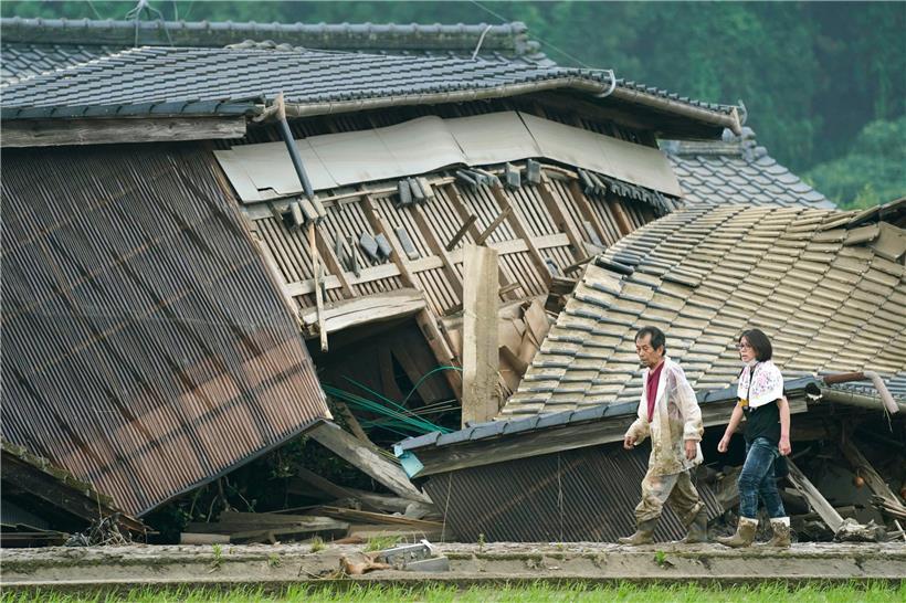 Ein Paar geht an Häusern vorbei, die durch eine Überschwemmung beschädigt wurden. Sintflutartige Regenfälle haben im Südwesten Japans massive Überflutungen und Erdrutsche verursacht und mehrere Menschen in den Tod gerissen.
