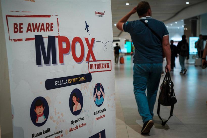 Ein Passagier geht am Soekarno-Hatta International Airport in Tangerang an einem Transparent vorbei, das über die Affenpocken (Mpox) informiert
