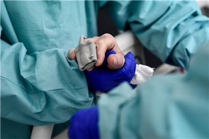 Ein Pfleger mit Handschuhen hält die Hand eines Covid-19-Patienten
