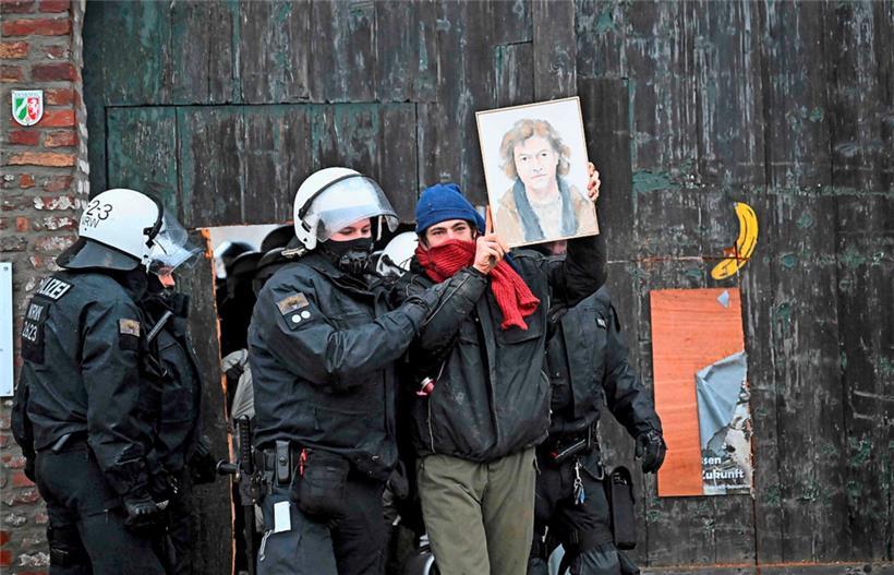 Ein Polizist führt einen Umweltschützer mit einem Porträt eines Landwirts ab, der lange Zeit für seinen Hof kämpfte und als letzter Einwohner von Lützerath zum Symbol der Klimabewegung wurde
