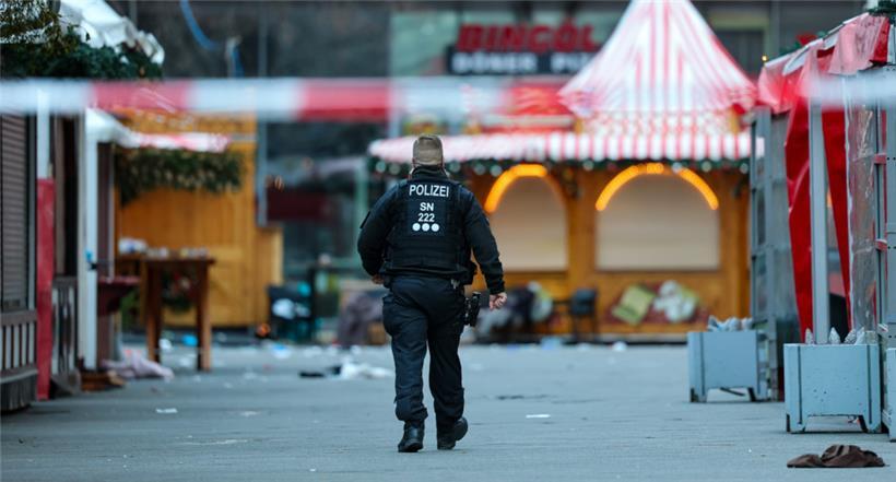 Ein Polizist geht hinter einer Absperrung am Magdeburger Weihnachtsmarkt
