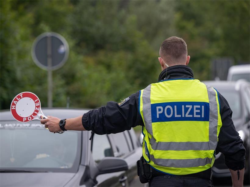 Ein Polizist hält Fahrzeuge an der Grenze zu Deutschland an