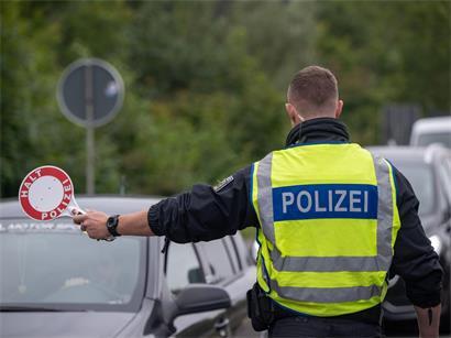 Ein Polizist hält Fahrzeuge an der Grenze zu Deutschland an
