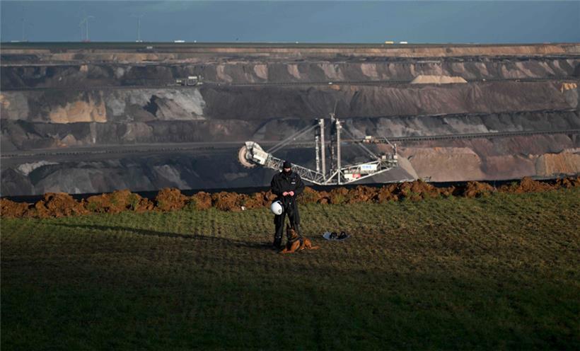 Ein Polizist mit einem Hund steht am 11. Januar 2023 am Rande der Braunkohlegrube im westdeutschen Dorf Lützerath
