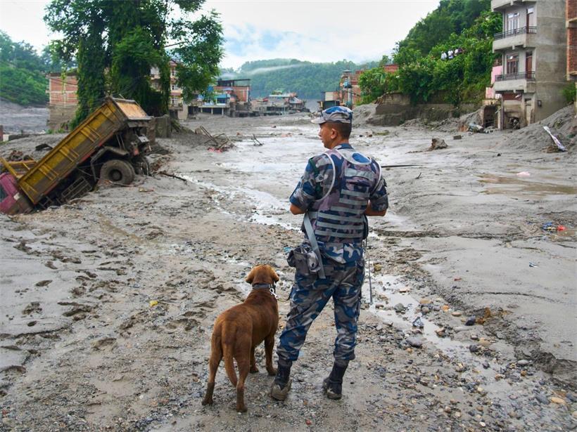 Ein Polizist mit einem Spürhund begutachtet die Schäden nach Sturzfluten in Devighat im Distrikt Nuwakot