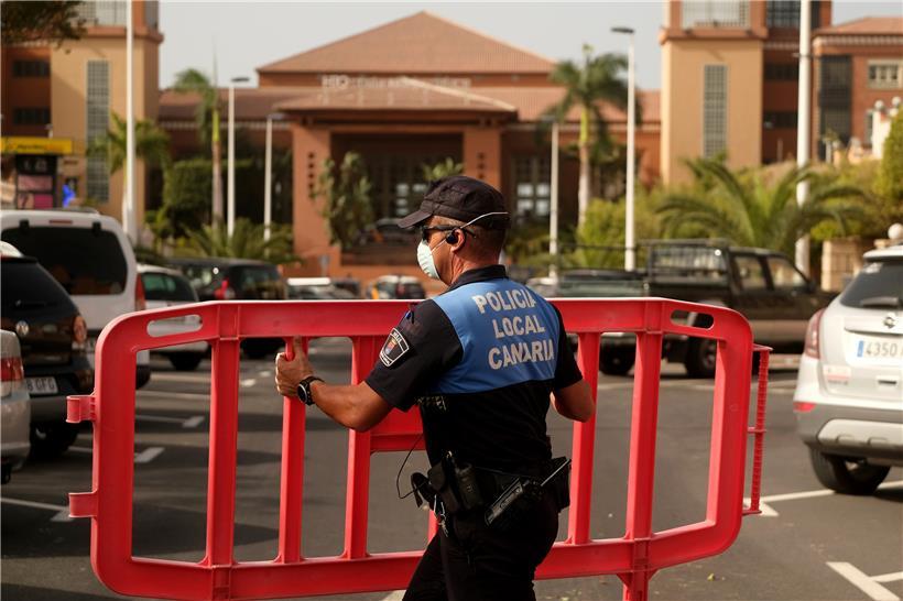 Ein Polizist setzt eine Sperre, die den Zugang zum Hotel H10 Costa Adeje Palace auf Teneriffa blockiert
