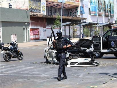 Polizist bewacht verbranntes Auto in Guadalajara nach Tod von Drogenboss El Mencho durch mexikanische Streitkräfte
