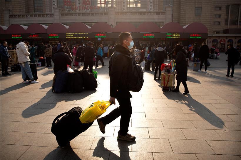 Ein Reisender trägt einen Mundschutz, während er vor dem Pekinger Bahnhof entlanggeht
