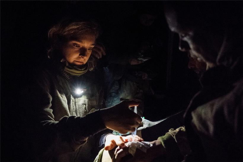 Ein Sanitäter versorgt einen verletzten Soldaten an einer Krankenstation, nachdem er aus einer von den Russen angegriffenen Stellung evakuiert wurde
