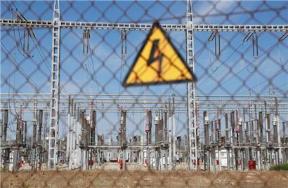 Ein Schild „Gefährliche elektrische Spannung“ hängt an einem Zaun in einem Umspannwerk
