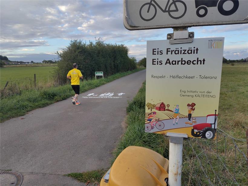 Ein Schild und ein gesprühtes Piktogramm rufen zu mehr Respekt auf dem Feldweg auf
