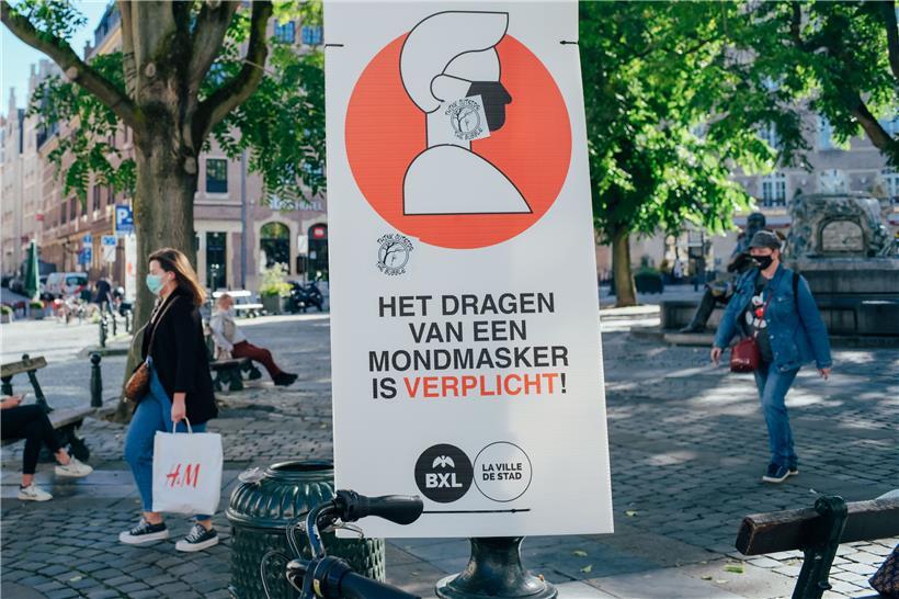 Ein Schild weist in einer Brüsseler Fußgängerzone auf die wegen der Corona-Pandemie geltende Maskenpflicht hin
