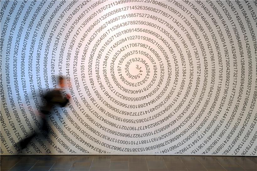 Ein Schulkind läuft im Mitmach-Museum „Mathematikum“ an der auf eine Wand geschriebenen Kreiszahl Pi vorbei
