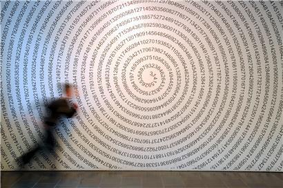 Ein Schulkind läuft im Mitmach-Museum „Mathematikum“ an der auf eine Wand geschriebenen Kreiszahl Pi vorbei

