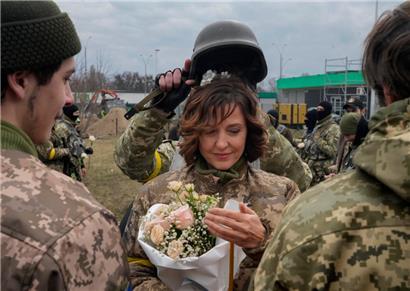 Ein Soldat hält am Sonntag, 6.3, in Kiew einen Helm als Hochzeitskrone während der Hochzeitszeremonie für die Mitglieder der ukrainischen Territorialen Verteidigungskräfte, Lesia Ivashchenko und Valerii Fylymonov, an einem Kontrollpunkt in Kiew 
