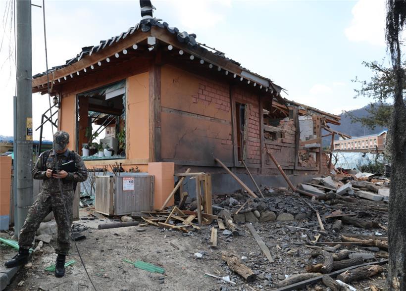 Ein Soldat steht vor einem Haus in Trümmern. Das Haus wurde bei einem versehentlichen Kampfjet-Bombenabwurf auf ziviles Gebiet beschädigt
