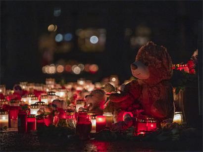 Ein Teddybär steht zusammen mit zahlreichen Kerzen auf dem Boden