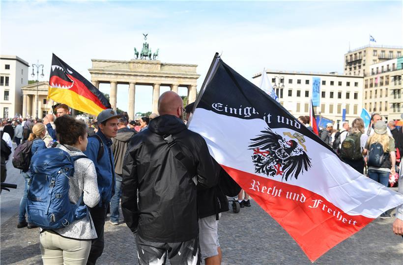Ein Teilnehmer hält vor der Demonstration gegen die Corona-Maßnahmen eine Reichsflagge vor dem Brandenburger Tor
