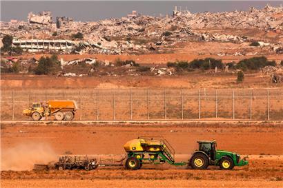 Ein Traktor bearbeitet vor dem Grenzzaun zum Gazastreifen ein Feld in Südisrael 

