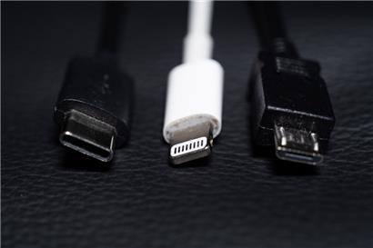 Ein USB-C (l-r), ein Apple Lightning und ein Micro-USB Kabel (l-r) liegen nebeneinander zu sehen

