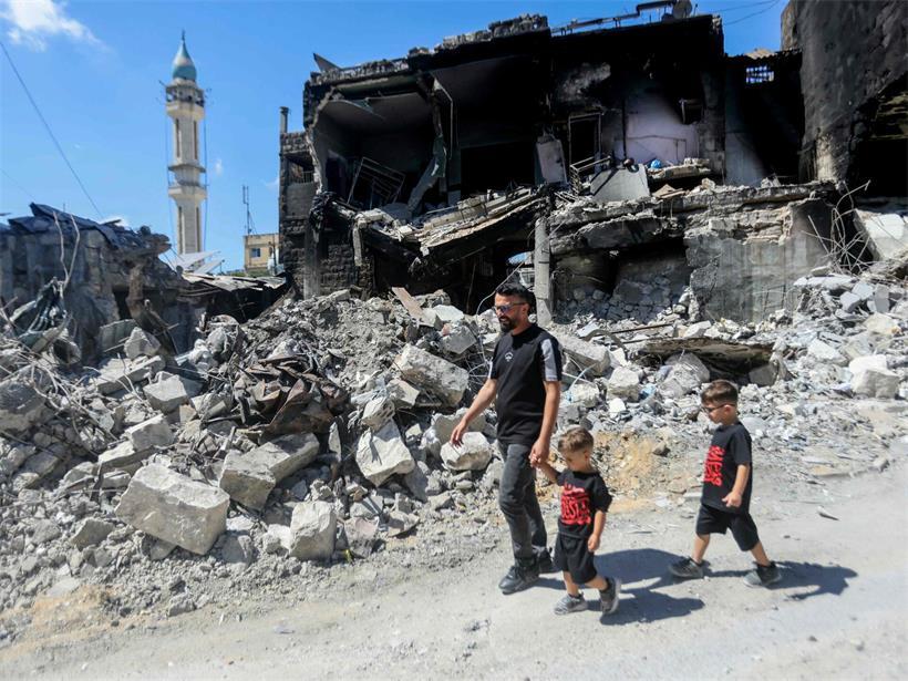 Vater geht in Nabatieh, Südlibanon, an den Ruinen eines im Krieg zerstörten Gebäudes vorbei