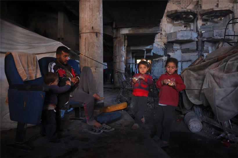 Ein Vater hat sich mit seinen Kindern in das zerstörte Auditorium der islamischen Universität in Gaza-Stadt zurückgezogen
