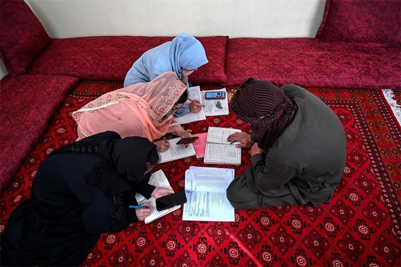 Ein Vater unterrichtet seine Töchter in ihrer Wohnung in Kabul