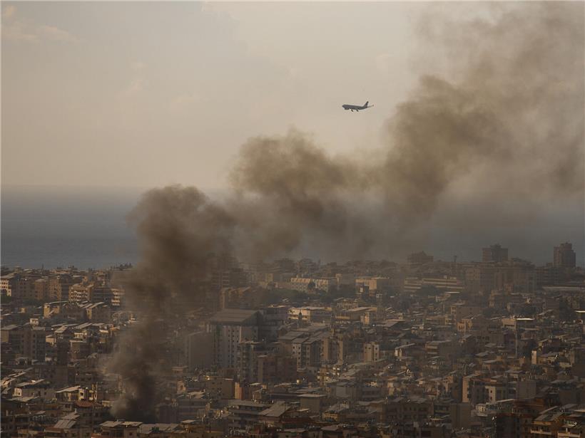 Verkehrsflugzeug landet am Flughafen Beirut, während Rauch von israelischen Luftangriffen auf südlichen Vorort aufsteigt