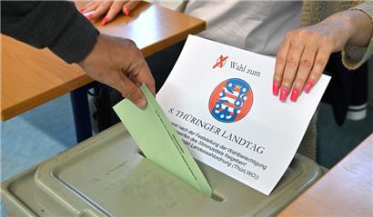 Ein Wähler steckt den Stimmzettel in die Wahlurne in einem Wahllokal in der Erfurter Innenstadt
