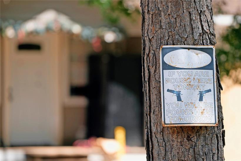 Ein Warnschild hängt an einem Baum vor dem Haus, in dem es am Freitagabend (28.4.2023) zu tödlichen Schüssen kam 
