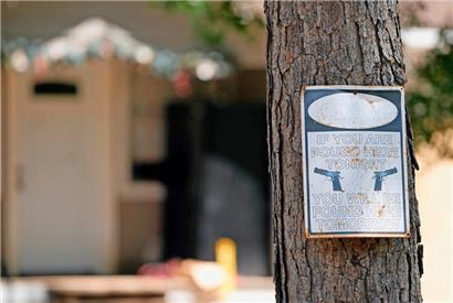 Ein Warnschild hängt an einem Baum vor dem Haus, in dem es am Freitagabend (28.4.2023) zu tödlichen Schüssen kam 
