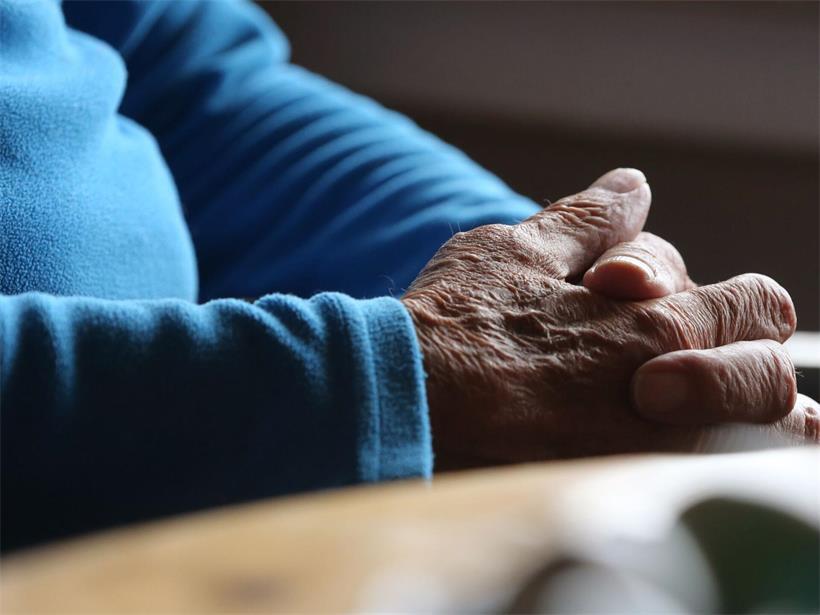 Ein älterer Mann sitzt in seiner Wohnung