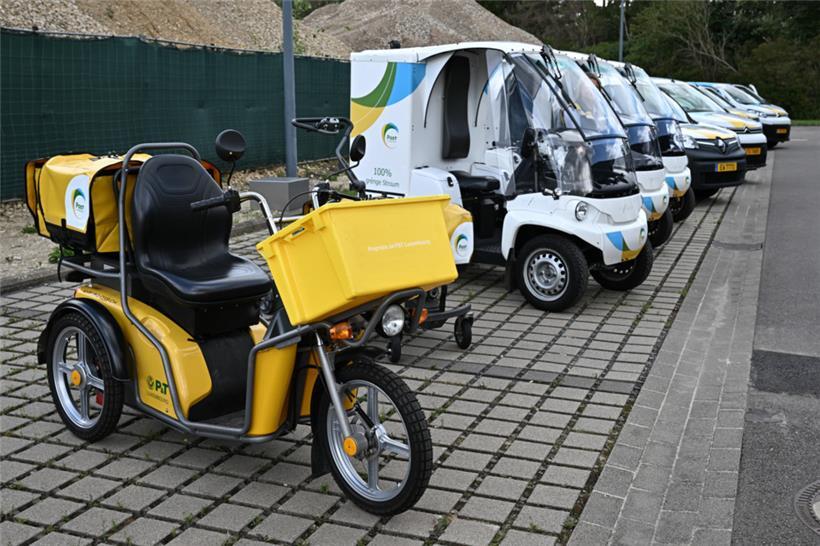 Ein älteres Elektro-Dreirad steht neben dem neuen elektrischen Zustellfahrzeug, dem Paxster
