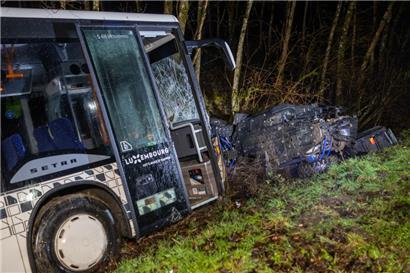 Ein beschädigter Bus und ein Auto liegen nach einem Unfall in einem Graben
