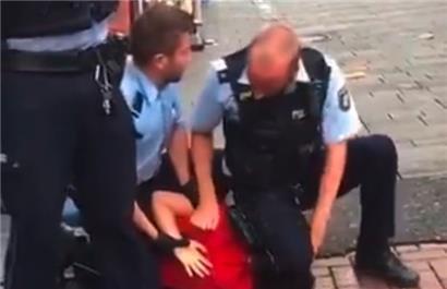 Ein deutscher Polizeibeamter kniet auf dem Hals eines jungen Mannes
