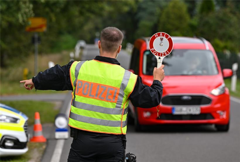 Ein deutscher Polizeibeamter stoppt ein Auto bei einer Kontrolle gegen Schleuserkriminalität. 
