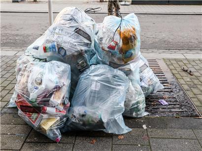 Plastiktüten stapeln sich unordentlich an Straßenlaterne, Umweltverschmutzung durch Plastikmüll im öffentlichen Raum