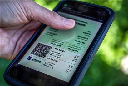 Ein israelischer Mann hält ein Smartphone in der Hand, auf dem der sogenannte „grüne Pass“ abgebildet ist, ein Zertifikat, das an Menschen ausgegeben wird, die vollständig geimpft sind
