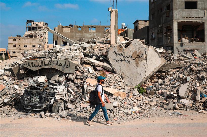 Ein palästinensischer Mann geht neben Trümmern, die mit Graffiti beschmiert sind, nach einem nächtlichen israelischen Angriff im Lager al-Bureij im zentralen Gazastreifen
