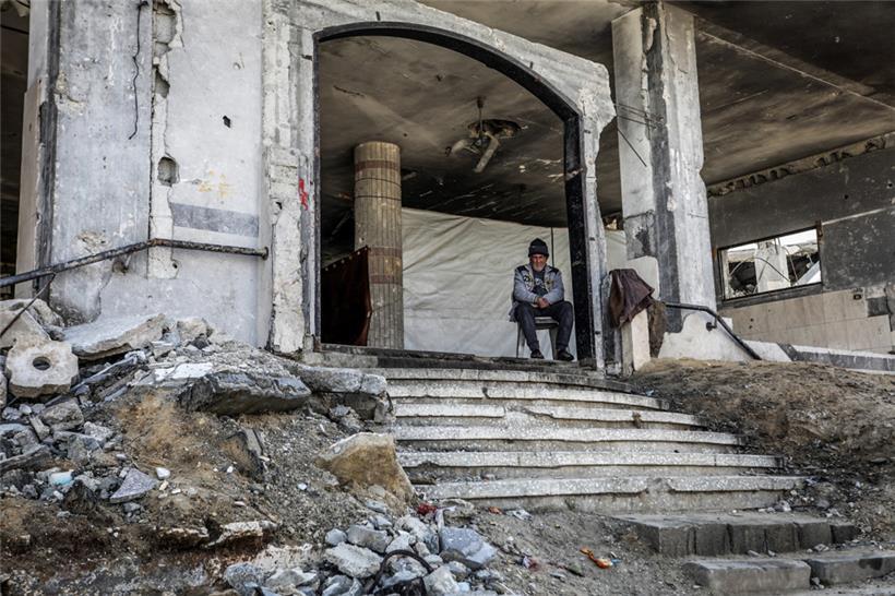 Ein palästinensischer Mann sitzt am Eingang eines zerstörten Gebäudes, nachdem sich die israelischen Streitkräfte im Rahmen der Waffenruhe mit der Hamas zurückgezogen haben
