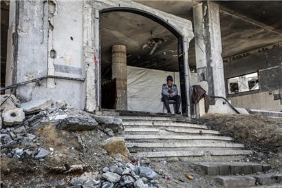 Ein palästinensischer Mann sitzt am Eingang eines zerstörten Gebäudes, nachdem sich die israelischen Streitkräfte im Rahmen der Waffenruhe mit der Hamas zurückgezogen haben

