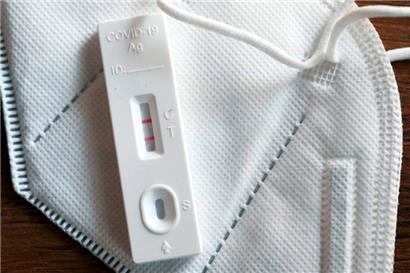 Ein positiver Corona-Selbsttest und eine FFP2-Schutzmaske liegen auf einem Tisch 
