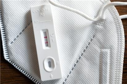 Ein positiver Corona-Selbsttest und eine FFP2-Schutzmaske liegen auf einem Tisch 
