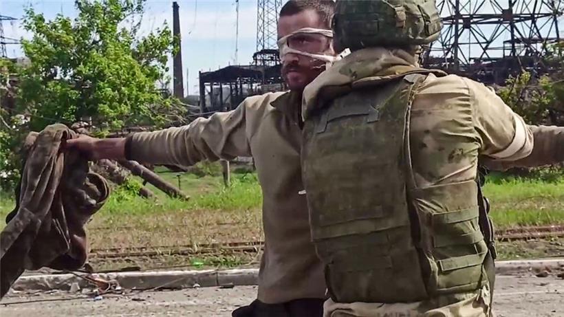 Ein russischer Soldat durchsucht einen ukrainischen Infanteristen nach der Evakuierung
