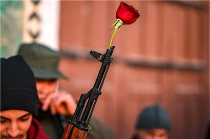Ein syrischer Rebellenkämpfer legt eine Rose an die Spitze des Laufs eines Sturmgewehrs
