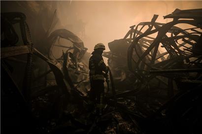 Ein ukrainischer Feuerwehrmann zieht einen Schlauch durch ein großes Lebensmittellager, das in den frühen Morgenstunden am Stadtrand von Kiew durch einen Luftangriff zerstört wurde
