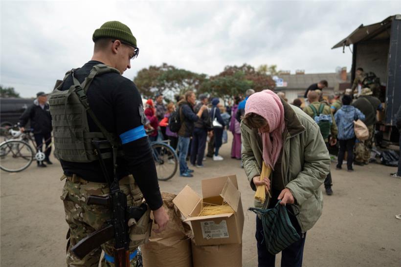 Ein ukrainischer Soldat des Sophia-Bataillons verteilt humanitäre Hilfe an eine Frau
