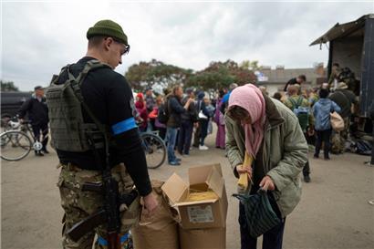 Ein ukrainischer Soldat des Sophia-Bataillons verteilt humanitäre Hilfe an eine Frau
